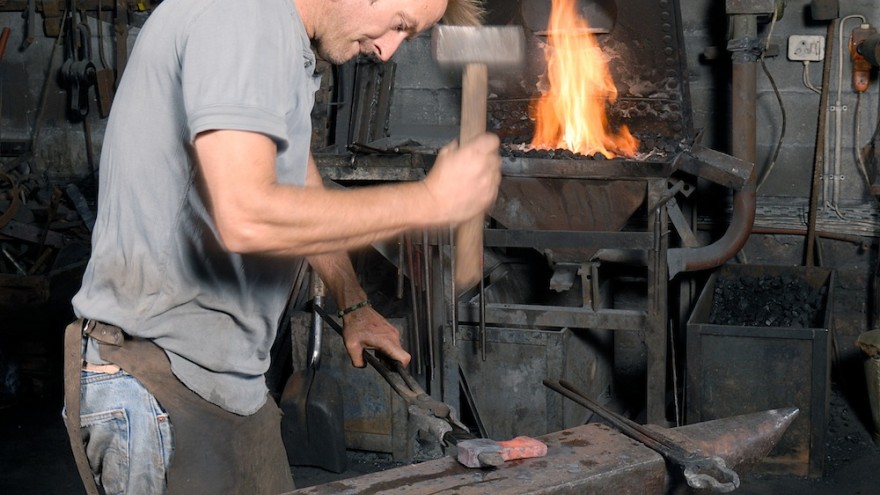 Conrad Hicks at the anvil in his forge. Image: Geof Kirby. 