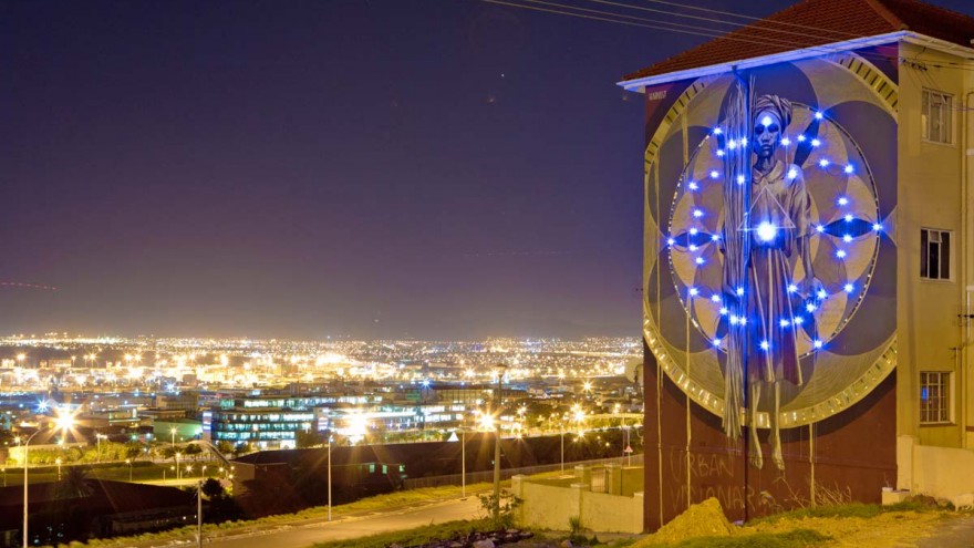 Harvest mural by Faith47 lit up at night. Photo by Rowan Pybus @Makhulu_