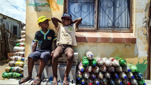 Two small children from Walmer Township in Port Elizabeth sit next to the EcoBricks that have been made for the Penguins Play and Learn Centre