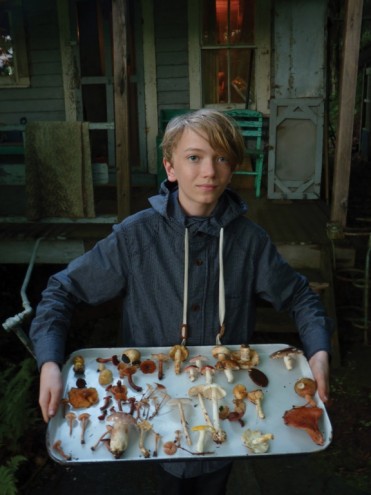 Young hunter, Leander Johnson poses with mushroom specimens in front of the old 
