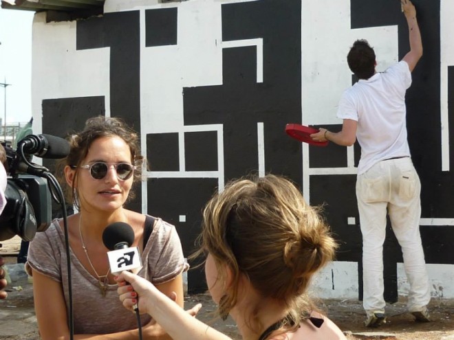 Les Petites Pierres co-founcer Maya Verichon interviewed in front of a mural by street artist Atlas during the 2012 Festival Interference.