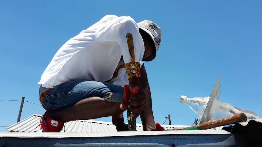 Installing a solar light made from an old plastic drinks bottle.