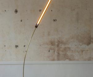 This brass and walnut wood lamp sways gently, mimicking a blade of grass in the wind. 