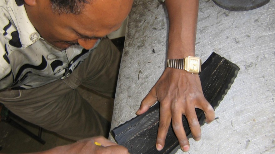 An artisan at soleRebels cuts the sole for a shoe out of an old car tyre.