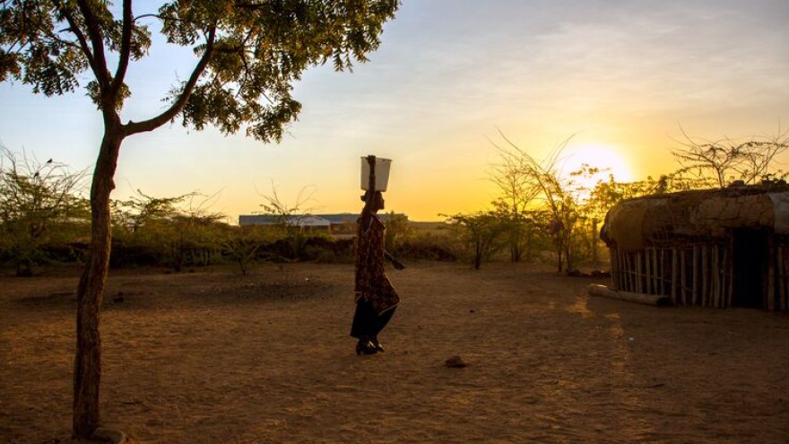 Rose Lekanta, 24 carries water to her home at dawn.