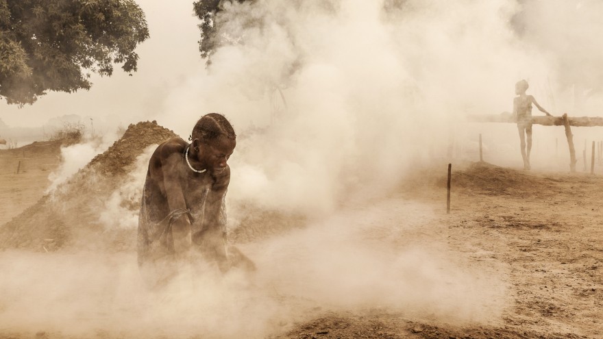 A Mundari woman clears the ground of sticks and dung before the cattle return home from the pastures. Women also milk the animals and look after the children. Image: © Tariq Zaidi / ZUMA Press