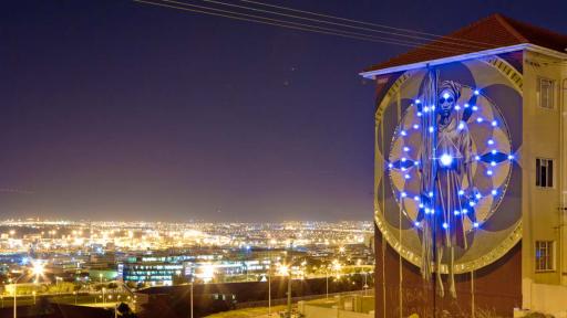 Harvest mural by Faith47 lit up at night. Photo by Rowan Pybus @Makhulu_