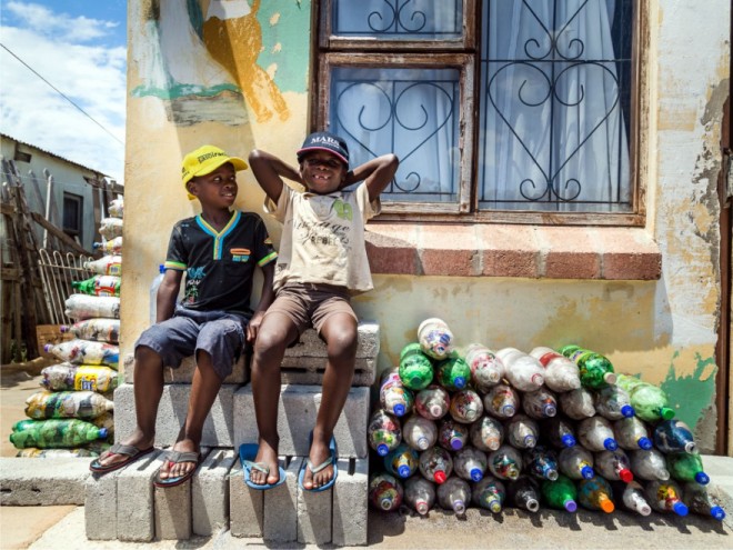 Two small children from Walmer Township in Port Elizabeth sit next to the EcoBricks that have been made for the Penguins Play and learn Centre. 