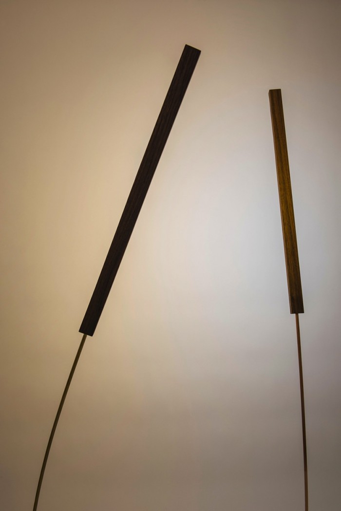 This brass and walnut wood lamp sways gently, mimicking a blade of grass in the wind. 