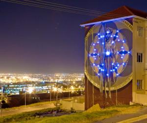 Harvest mural by Faith47 lit up at night. Photo by Rowan Pybus @Makhulu_