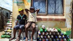 Two small children from Walmer Township in Port Elizabeth sit next to the EcoBricks that have been made for the Penguins Play and Learn Centre